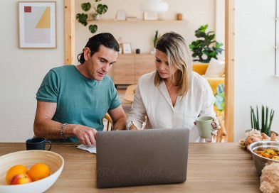 Couple checking bills to pay or domestic finances while going trough documents using laptop and sitting at the table at home.