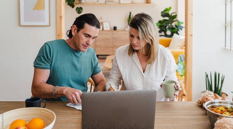 Couple checking bills to pay or domestic finances while going trough documents using laptop and sitting at the table at home.